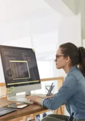software engineer writing code on a desktop computer in an Islamabad web development office.